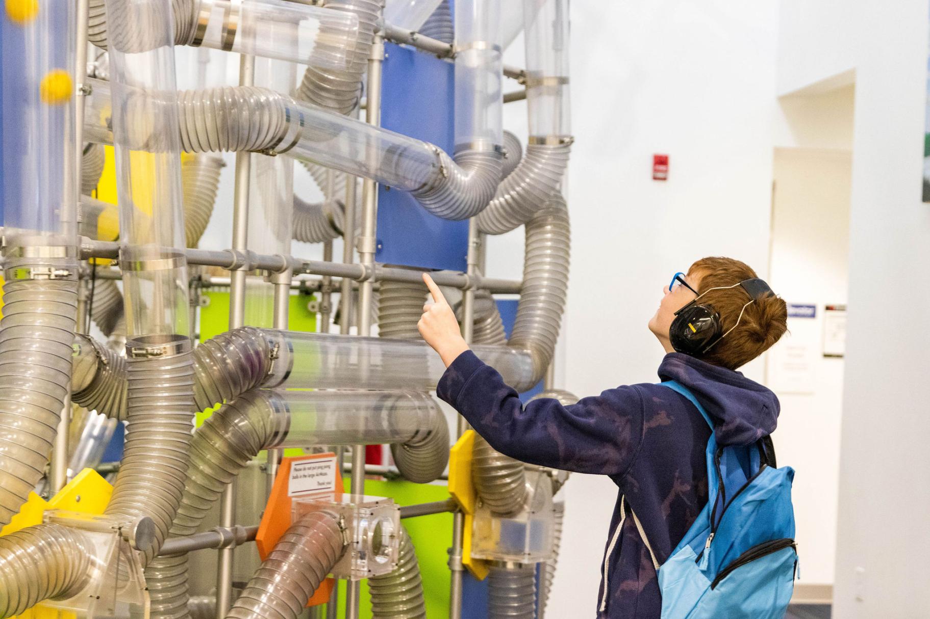 a boy wearing noise-cancelling headphones interacts with the Museum's AirPlay exhibit